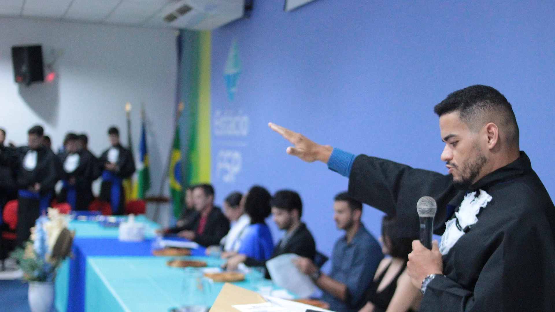 Solenidade de colação de grau com formandos reunidos no palco